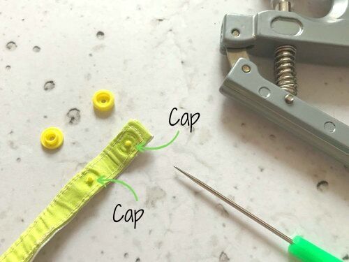 Stecke die Caps der Kam Snaps durch die Löcher.