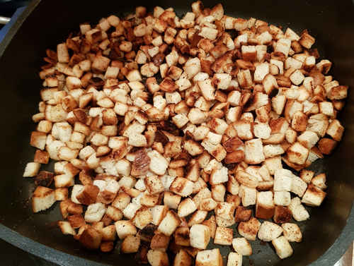 Für den Serviettenknödel, röstest Du die Weißbrotwürfel an.